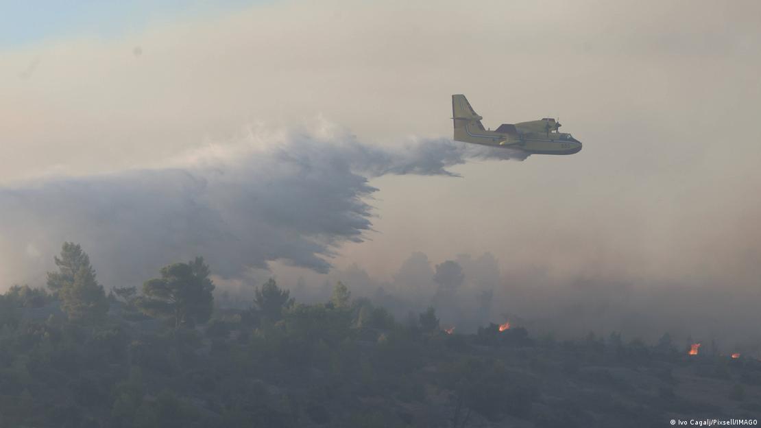 Un Canadair CL-415 de lucha contra incendios suelta su carga de agua sobre un bosque de Brac en el que se distinguen pequeñas zonas de llamas. Un Canadair CL-415 de lucha contra incendios suelta su carga de agua sobre un bosque de Brac en el que se distinguen pequeñas zonas de llamas.