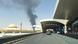 Coluna negra de fumaça no horizonte, com entrada do Aeroporto Internacional Rei Khalid, em primeiro plano