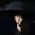Presiden ASW Donald Trump berjalan memegang payung.