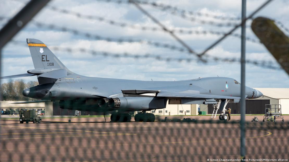 Un bombardero B-1 Lancer de la Fuerza Aérea de los EE. UU. visto a través de la valla de la base RAF Fairford, bajo la mirada de aficionados a la observación de aviones. Un bombardero B-1 Lancer de la Fuerza Aérea de los EE. UU. visto a través de la valla de la base RAF Fairford, bajo la mirada de aficionados a la observación de aviones.