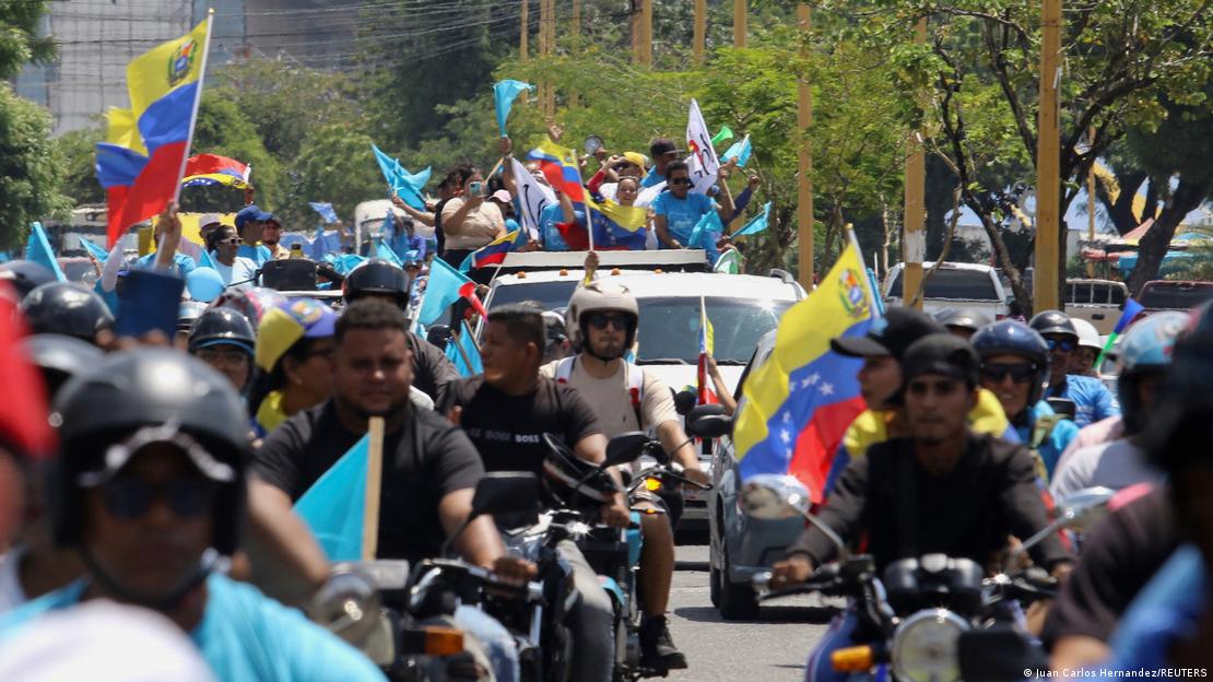 Manifestantes en moto por la calle, muchos ondean banderas de Venezuela.