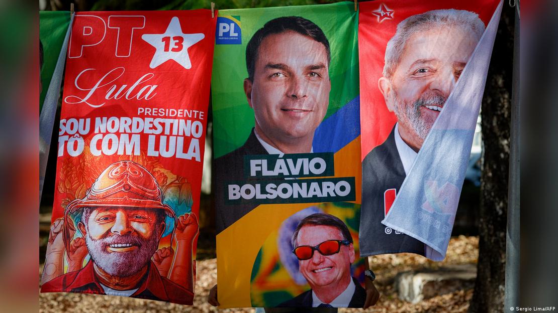 Tres coloridas toallas con imágenes de Lula y Flávio Bolsonaro.