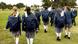Rückansicht von Schülerinnen und Schülern in Schuluniform auf einer Wiese Rückansicht von Schülerinnen und Schülern in Schuluniform auf einer Wiese