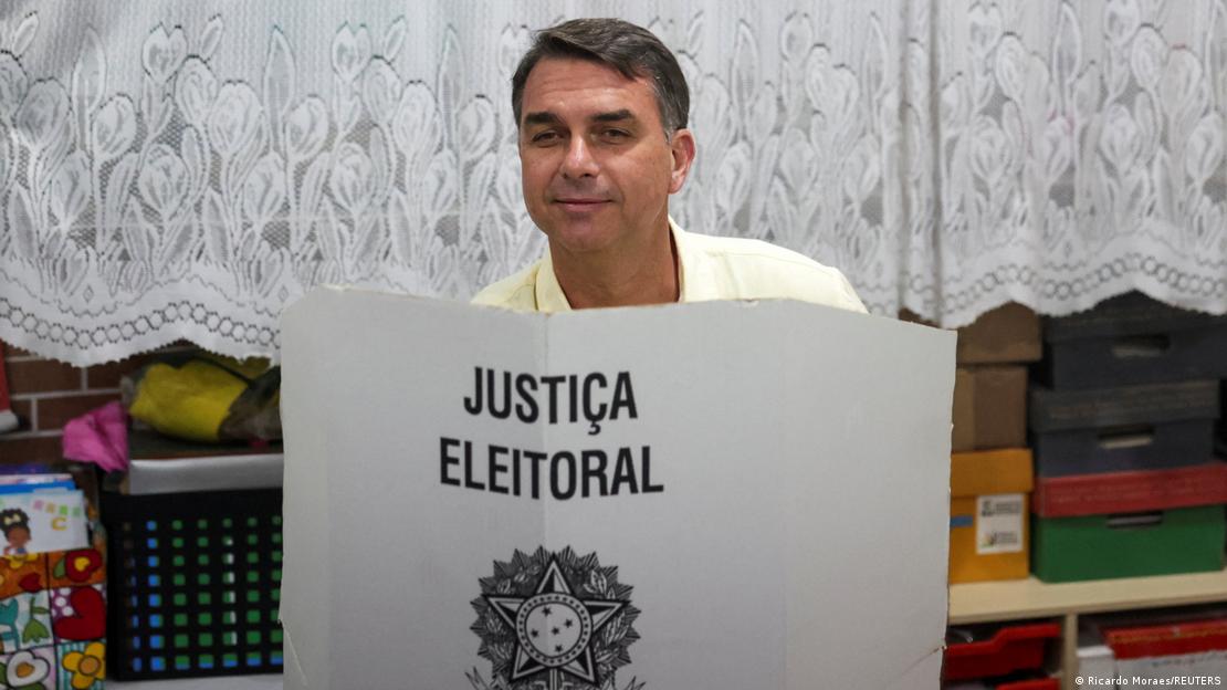 Flávio Bolsonaro acude a depositar su voto. Su cabeza emerge tras un cartel blanco con letras negras, donde pone en portugués: "Justicia electoral". Flávio Bolsonaro acude a depositar su voto. Su cabeza emerge tras un cartel blanco con letras negras, donde pone en portugués: "Justicia electoral".
