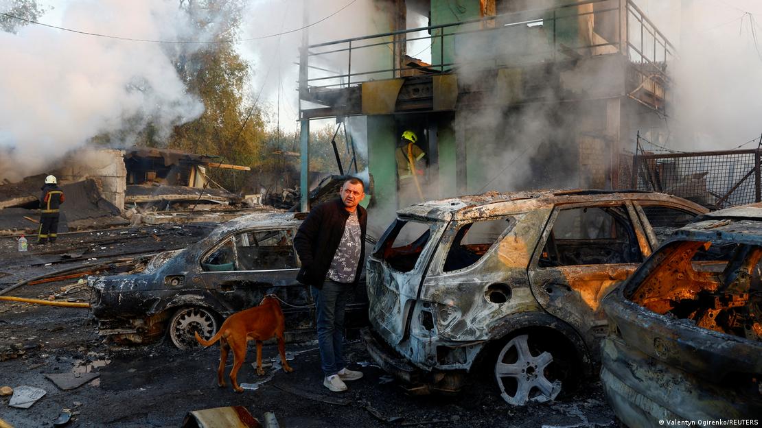 A resident with a dog looks on at the site of private car garages hit by a Russian missile strike, A resident with a dog looks on at the site of private car garages hit by a Russian missile strike,