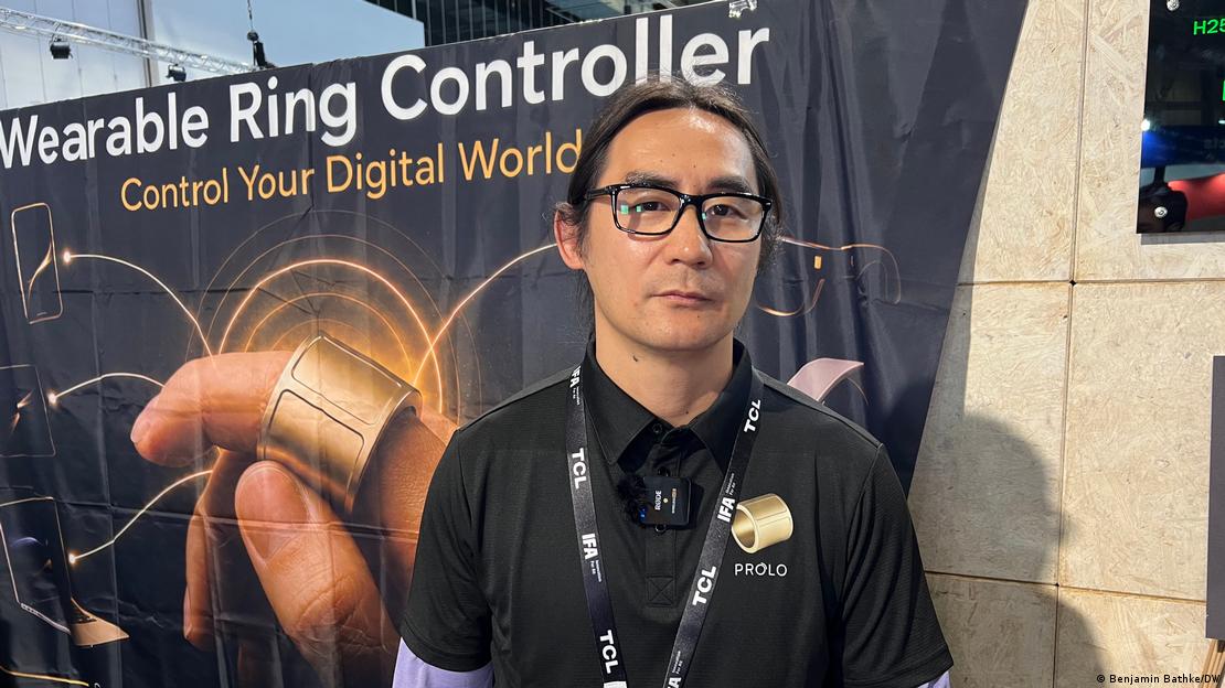Homem na faixa dos 30 a 40 anos, diante de stand em feira de tecnologia Homem na faixa dos 30 a 40 anos, diante de stand em feira de tecnologia