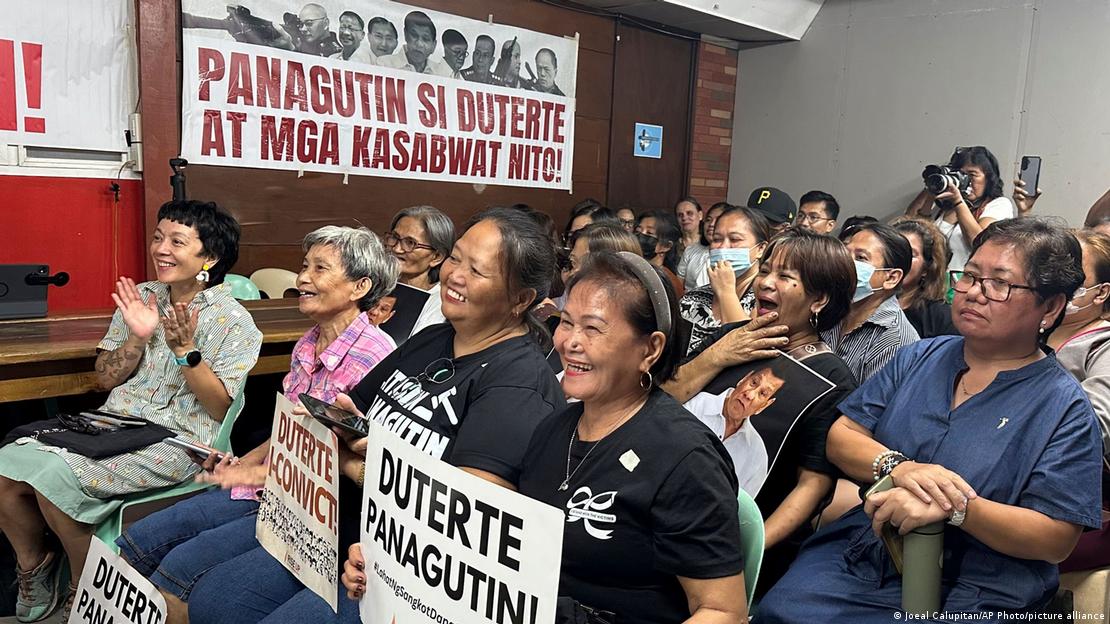 Image 1: Families of victims of former Philippine President Rodrigo Duterte's war on drugs react as they watch him on a screen during a hearing at the International Criminal Court, in Manila, Philippines, Wednesday, Sept. 16, 2026. A banner seen in the background reads "Hold Duterte and his accomplices accountable."