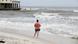 Image 4: A woman stands by the beach days before Hurricane Isaias is expected to make landfall
