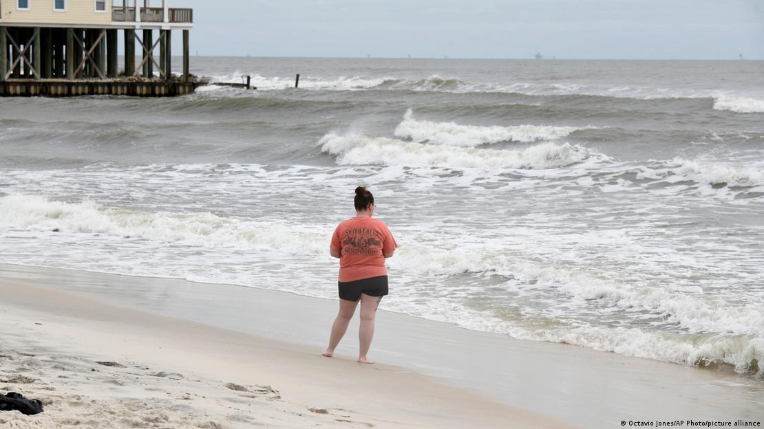 Image 5: A woman stands by the beach days before Hurricane Isaias is expected to make landfall