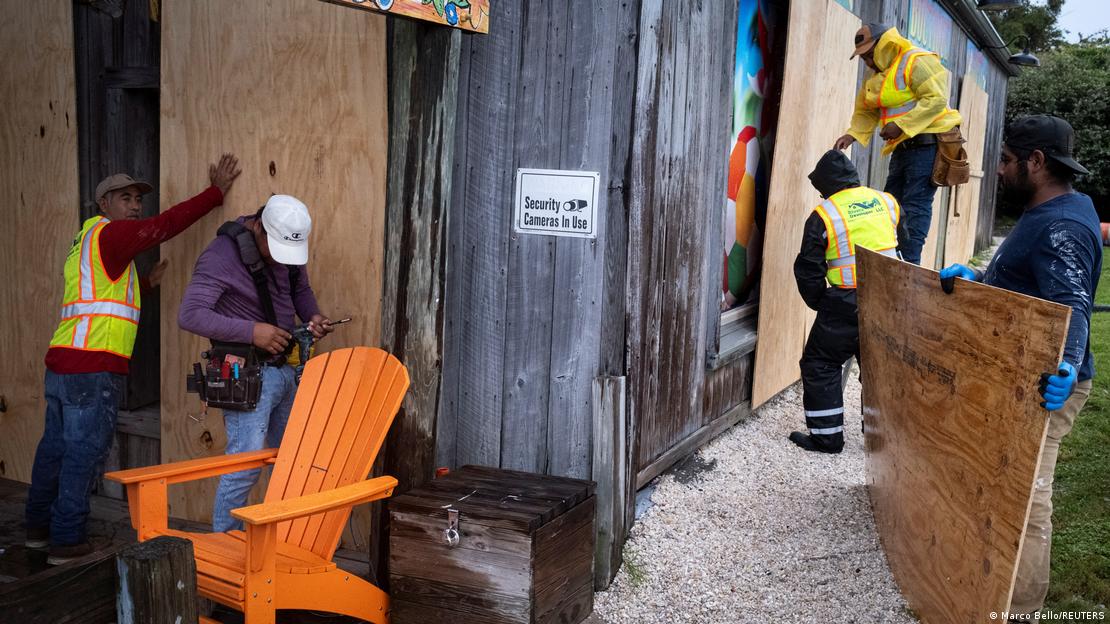 Men work boarding up a restaurant as Hurricane Isaias moves through the Gulf of Mexico and is forecast to strengthen before reaching the US gulf coast, in Pensacola Beach, Florid