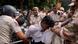 A man being dragged away by police officials A man being dragged away by police officials