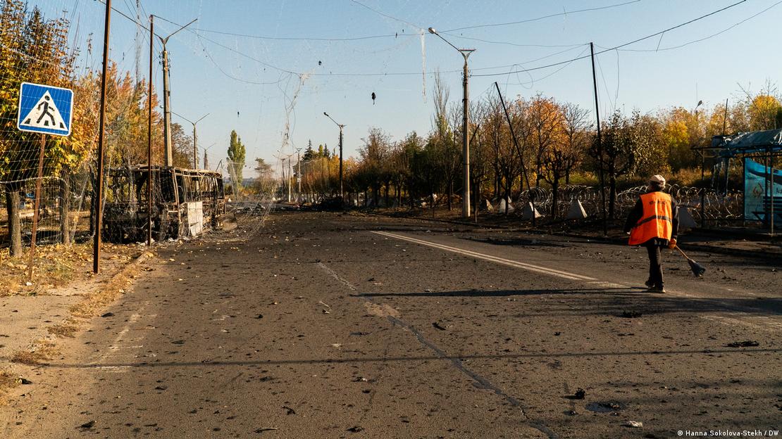 Сотрудник коммунальной службы убирает дорогу возле места, куда попала российская авиабомба