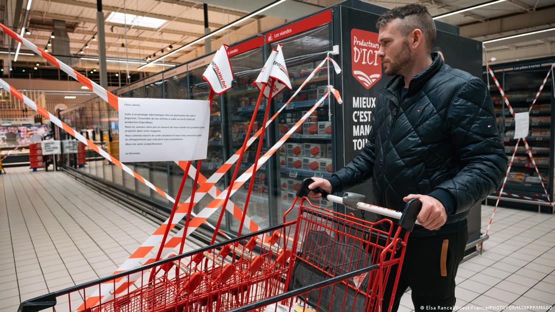Bir süpermarkette müşteri alışveriş arabasıyla ilerlerken soğutma reyonu güvenlik şeritleriyle çevrilmiş durumda.