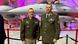 Two men (Dale Lyles and Slavomir Staviarsky) stand in front of an F-16 fighter jet in an indoor setting, Greenville, USA, February 29, 2024