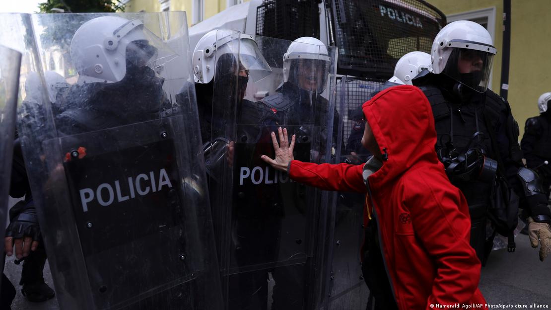 Albanien Tirana 2026 | Eine zivile Person hält ihre Hand abwehrend an das Plexiglasschild eines Polizisten in Schutzmontur (15.10.2026) Albanien Tirana 2026 | Eine zivile Person hält ihre Hand abwehrend an das Plexiglasschild eines Polizisten in Schutzmontur (15.10.2026)