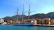 Ein großes Dreimast-Segelschiff an einer Hafenmauer, im Hintergrund Häuser, Berge und blauer Himmel Ein großes Dreimast-Segelschiff an einer Hafenmauer, im Hintergrund Häuser, Berge und blauer Himmel