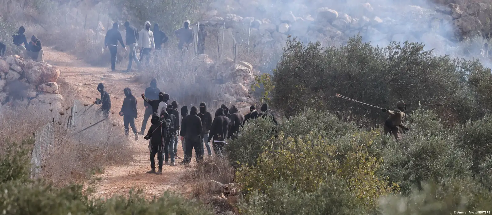 Palestinians look towards Israeli settlers casting projectiles amid clashes during olive harvest in Abu Falah near Ramallah in the Israeli-occupied West Bank