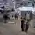 Palestinians walking through refugee camp in Gaza with tents and rubble in the background, on October 18, 2026
