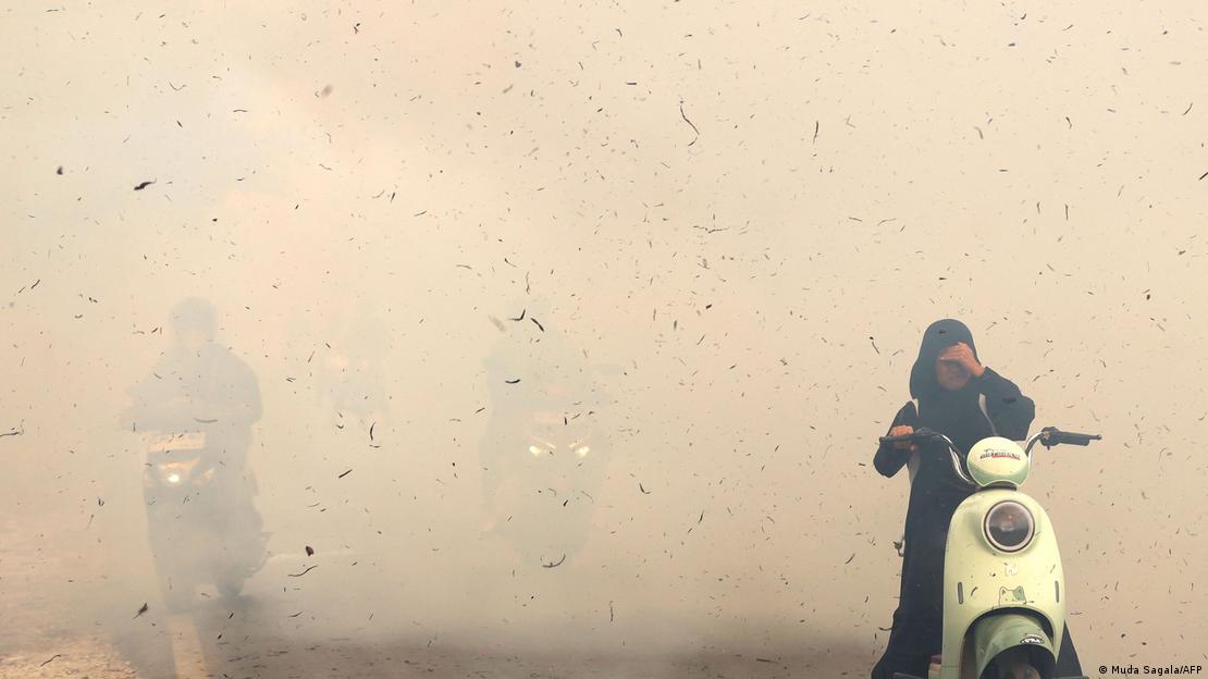 Motoristas passam por entre a fumaça de um incêndio na Indonésia.