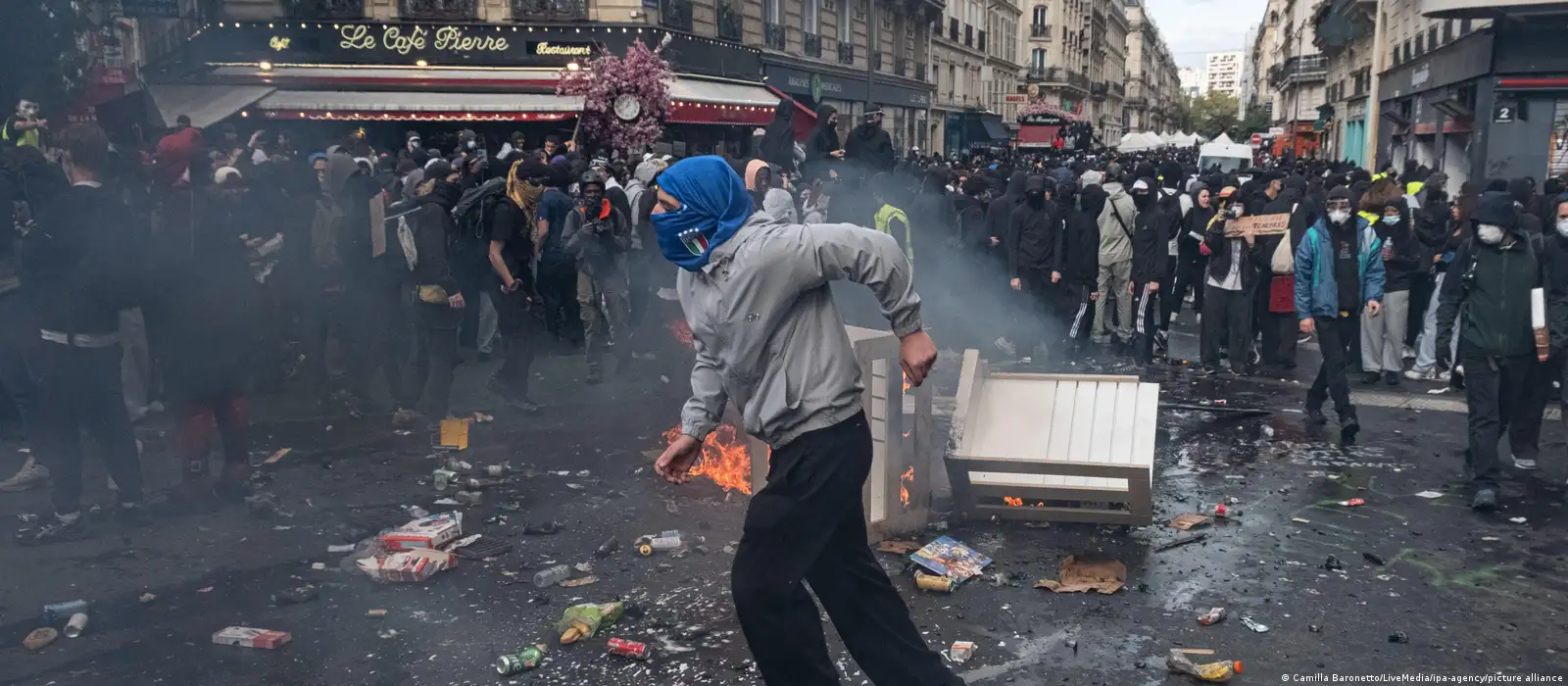 Paris'teki protestolarda bir gösterici, etrafa saçılmış cisimlerin ve kalabalığın ortasında