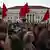 A crowd of people carrying red flags and placards in the streets of Lisbon