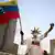 Venezuela Caracas 2026 | Ein Anhänger Machados schwenkt die venezolanische Flagge, sein Gesicht ist weiß geschminkt, auf seinem Kopf ein Haarreif, der der Strahlenkrone der Freiheitsstatue in New York ähnelt (22.10.2026)