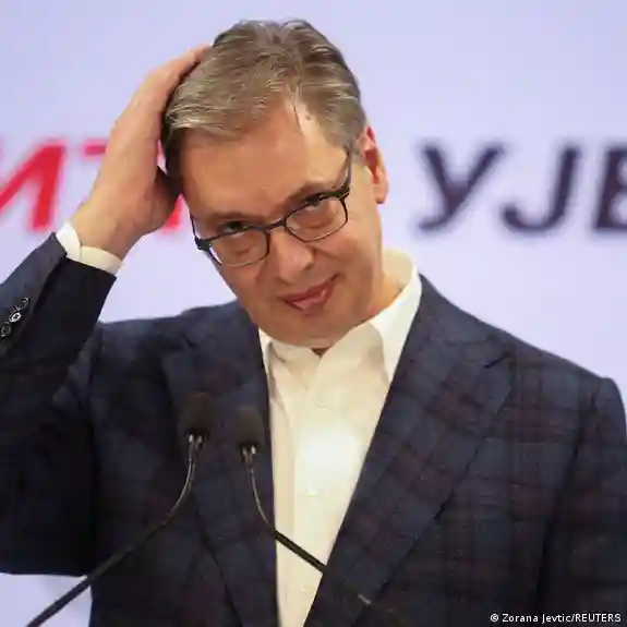 Aleksandar Vucic kürsüde görülüyor, sağ eli başının üzerinde