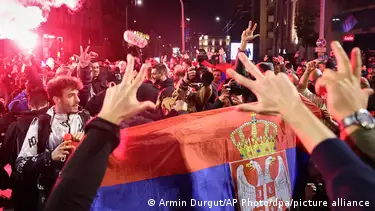 Büyük bir Sırbistan bayrağı etrafında kutlama yapan kalabalık