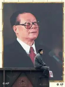 A worker rides on the last carriage of a train as it passes by a huge portrait of Chinese President Jiang Zemin at a factory in Beijing on the eve of the day Jiang's successor will be named Friday March 14, 2003. The National People's Congress, China's legislature, is expected to confirm Vice President Hu Jintao as Jiang's replacement in a vote Saturday. (AP Photo/Greg Baker)
